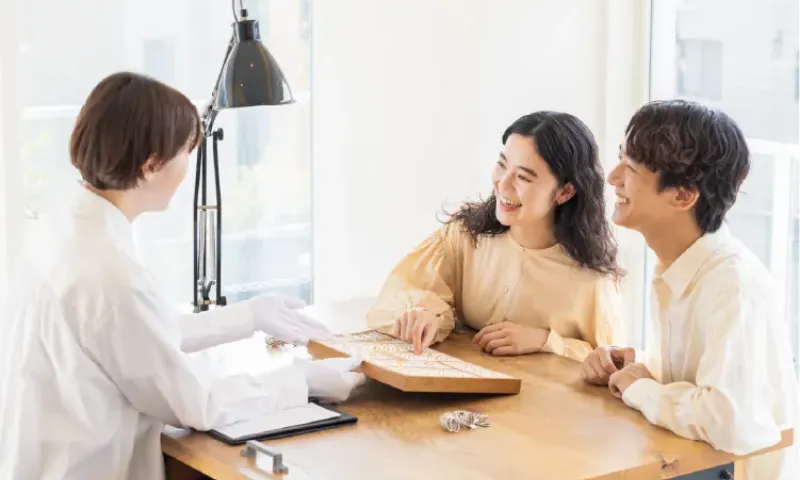 店員と指輪を見ながら笑顔で相談するカップル