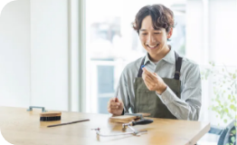 作業台で指輪を手に微笑む職人